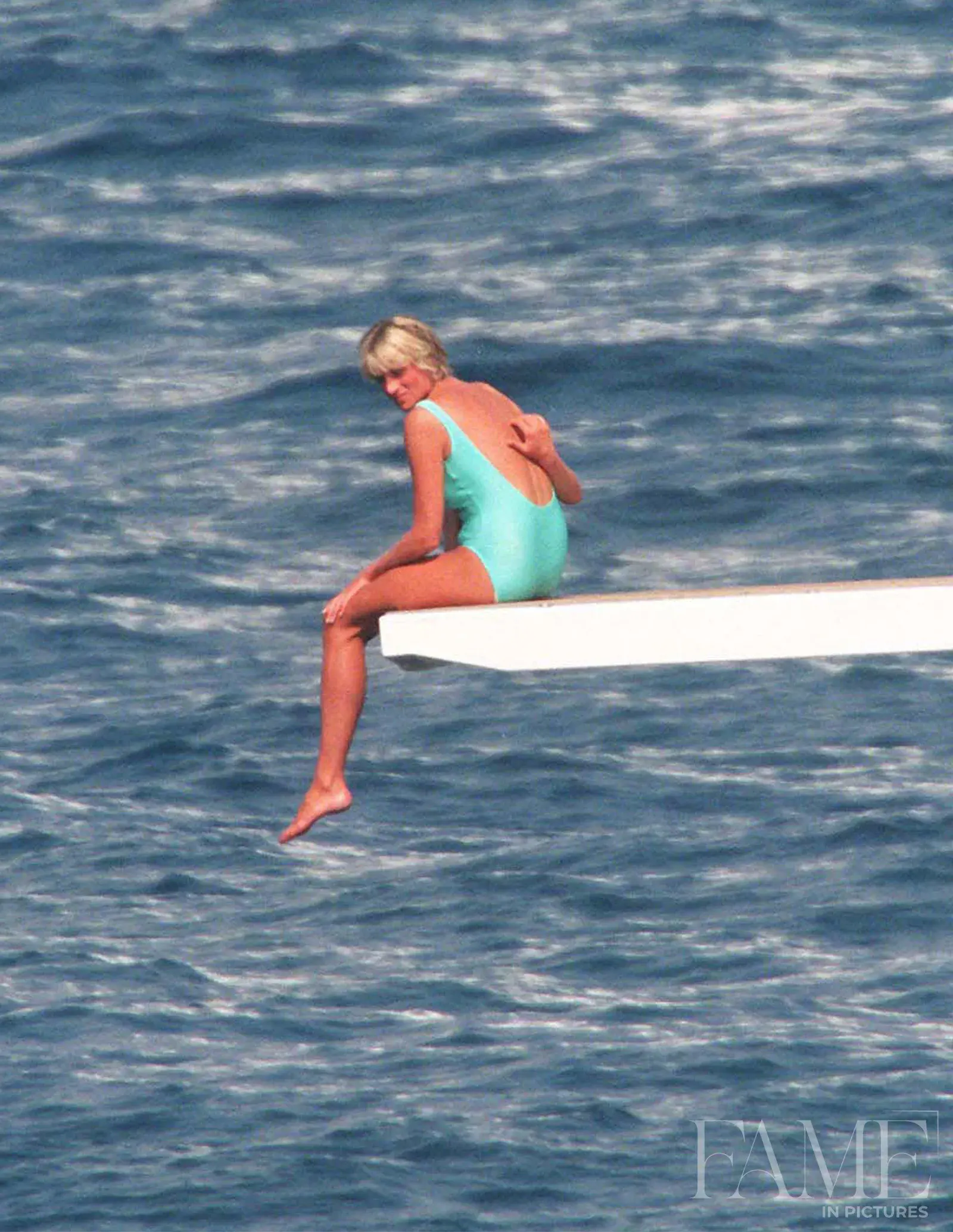 Princess Diana turning while seated on a yacht diving board near Portofino in 1997
