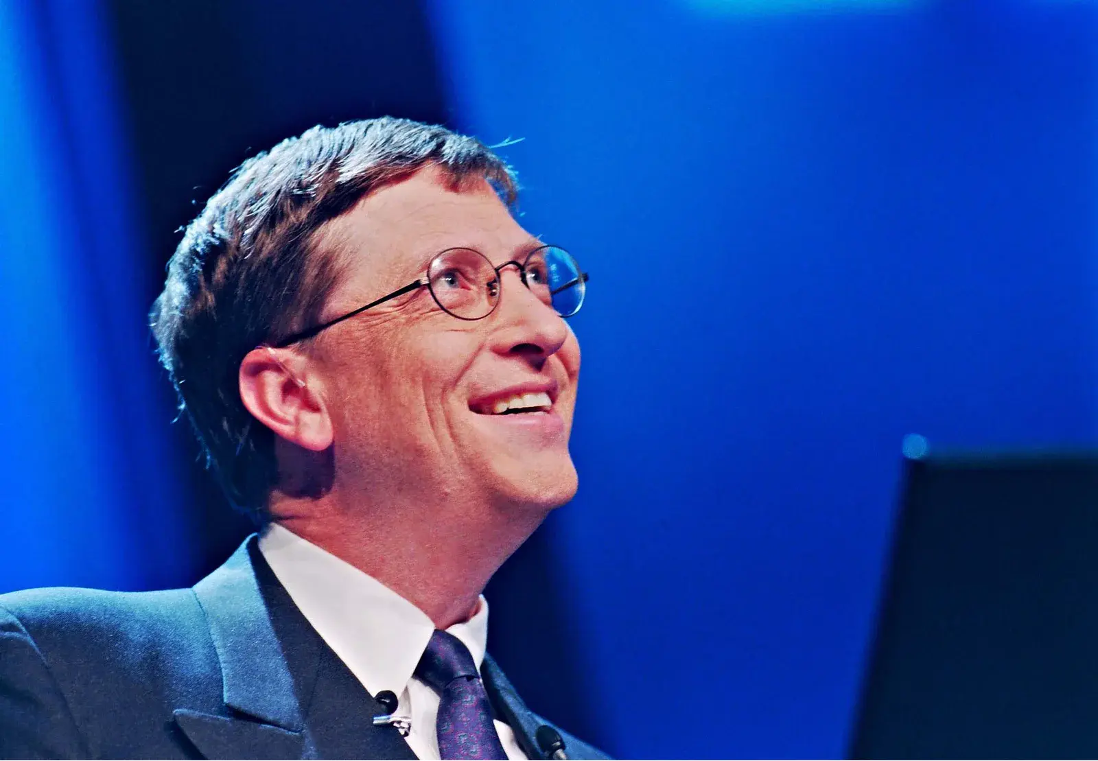 Bill Gates smiling in a horizontal portrait at a Paris internet seminar in 1998