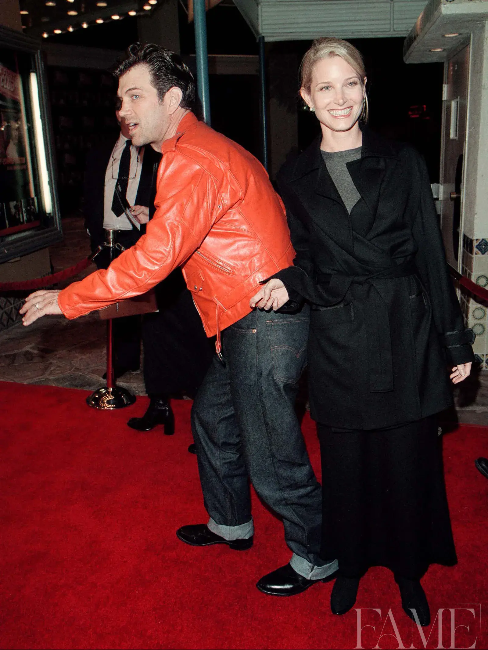 Chris Isaak wearing an orange leather jacket beside Bridget Fonda at the Fight Club premiere