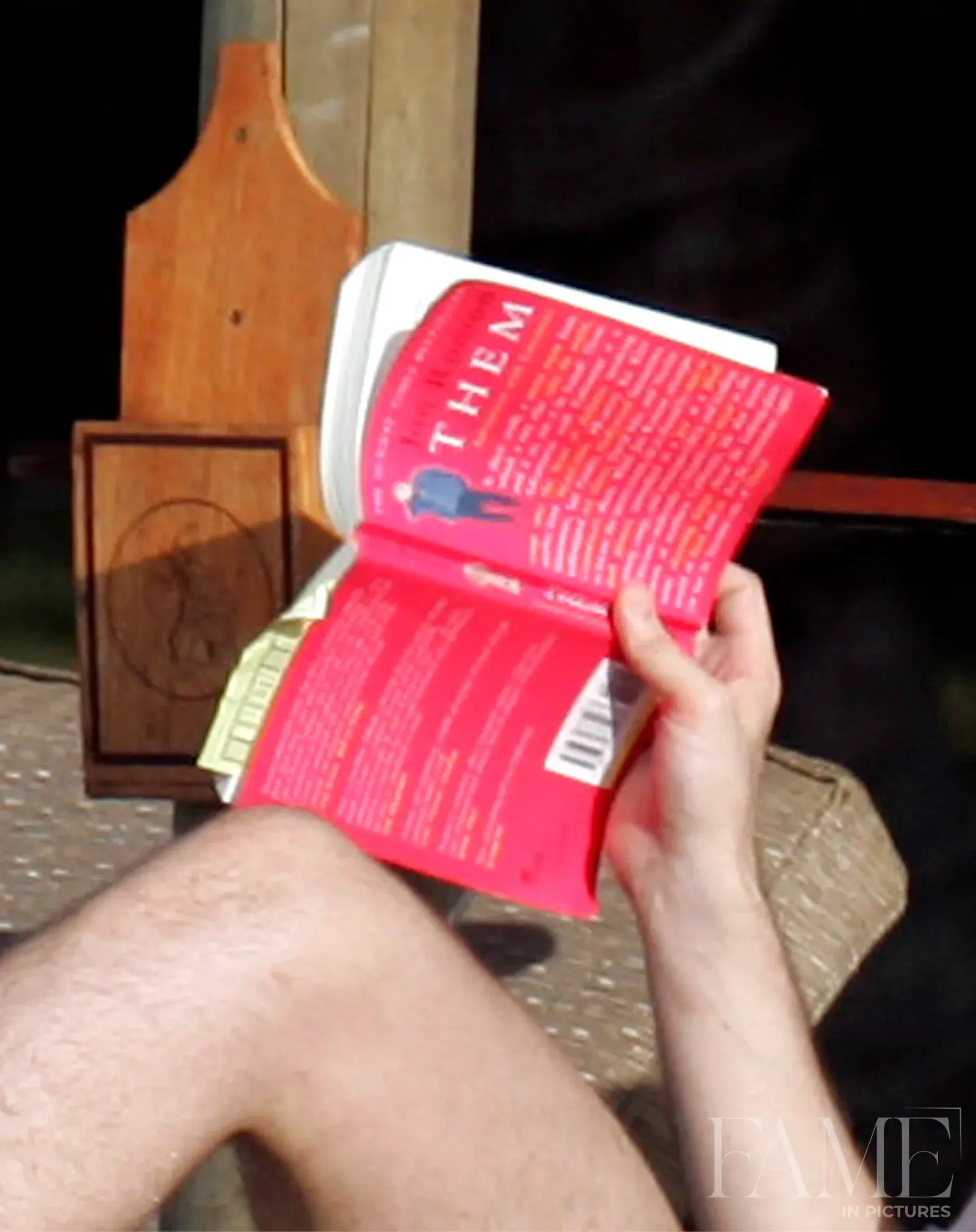 A person holding an open copy of Them: Adventures with Extremists, their face obscured by the book.