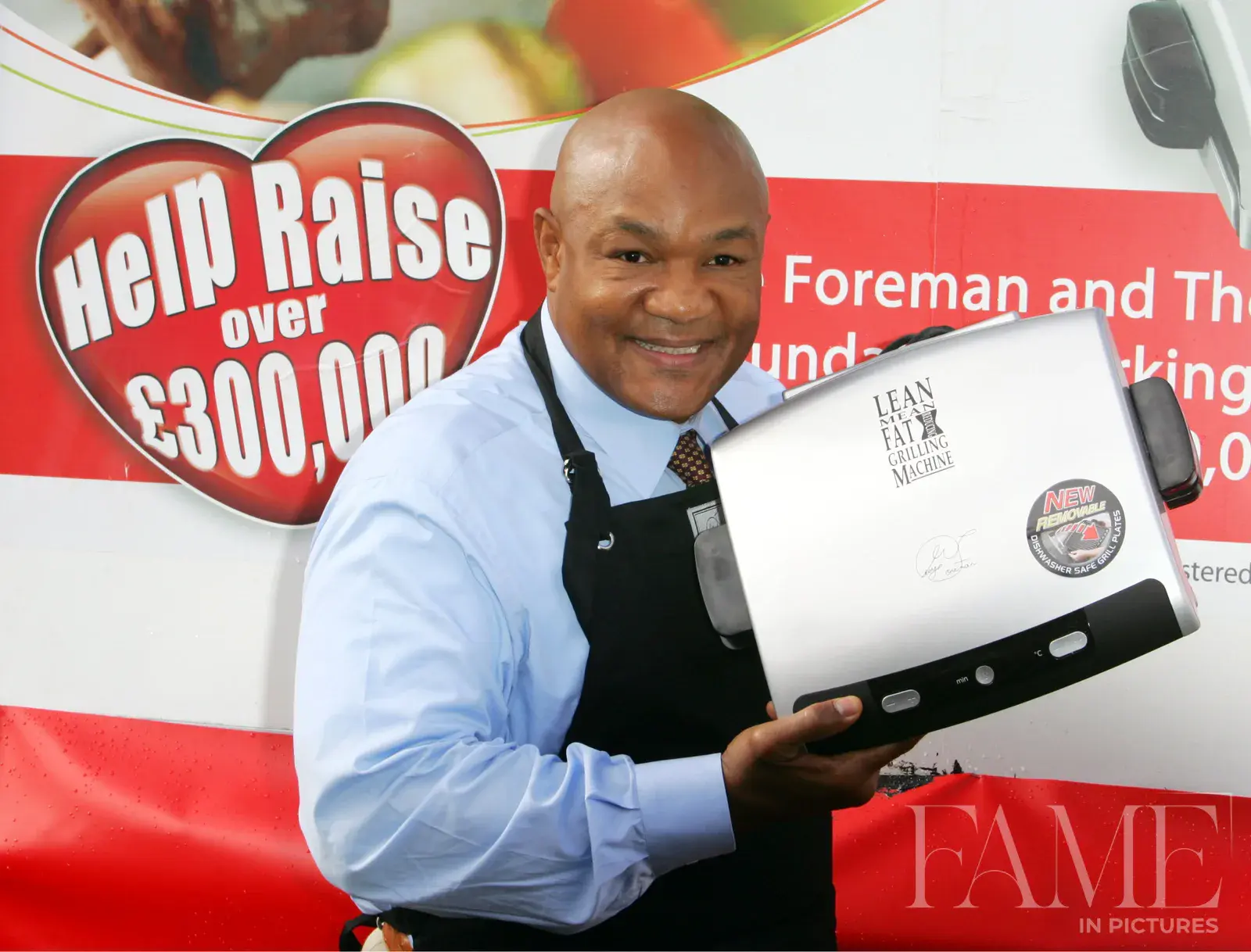 George Foreman holding a grill beside a red fundraising display in Trafalgar Square