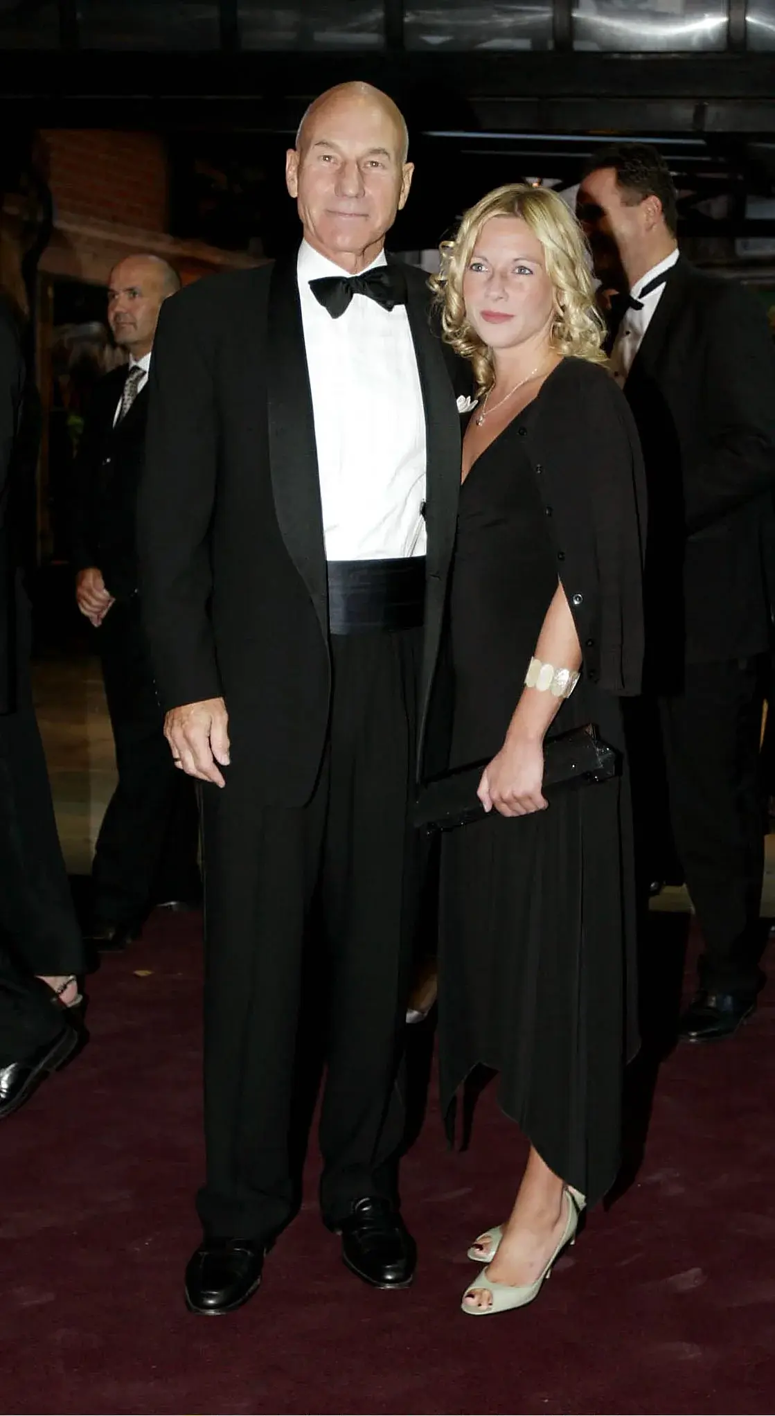 Patrick Stewart in a dinner jacket and bow tie arriving with a guest at a theatre opening