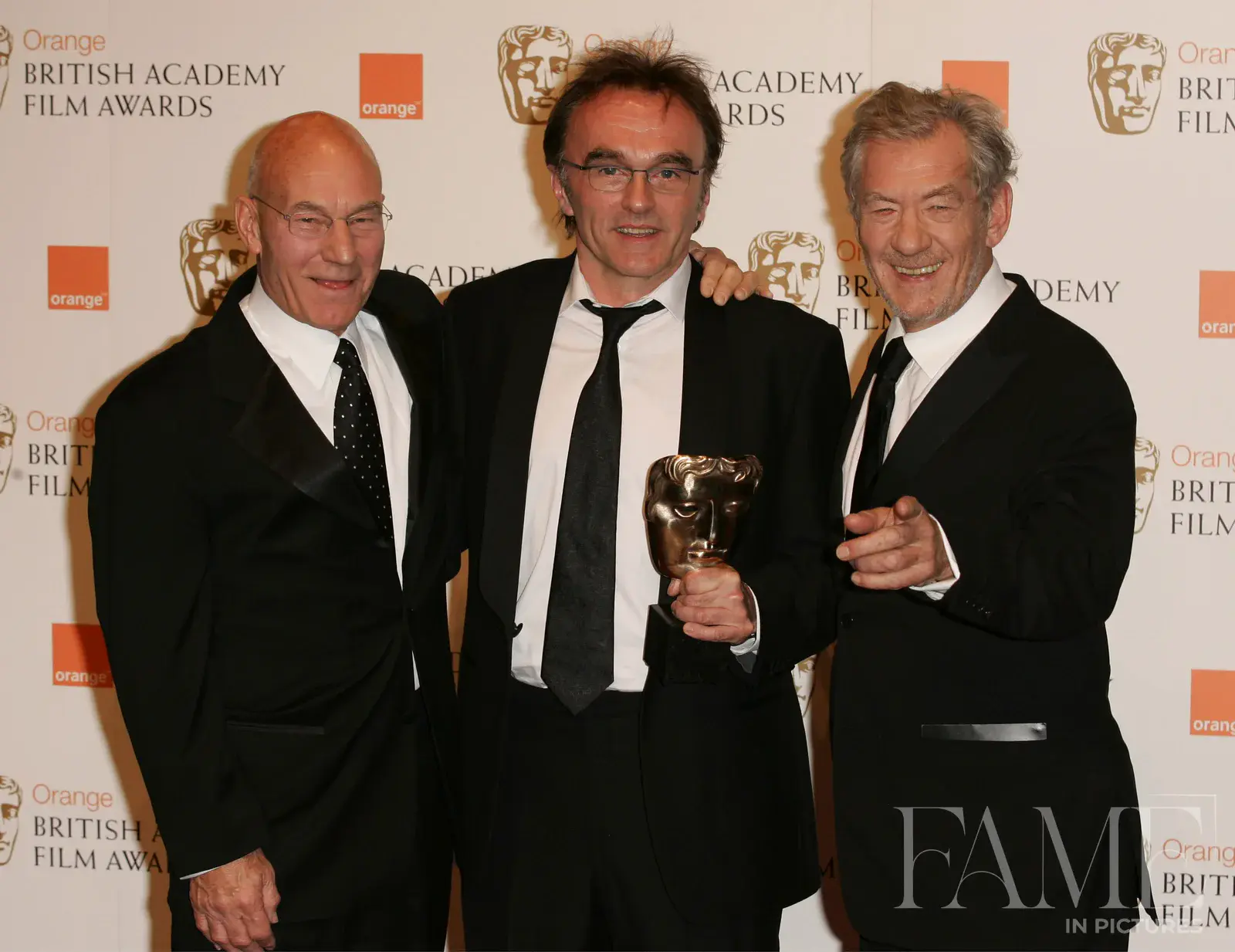 Patrick Stewart, Danny Boyle and Ian McKellen smiling together in the BAFTA awards room